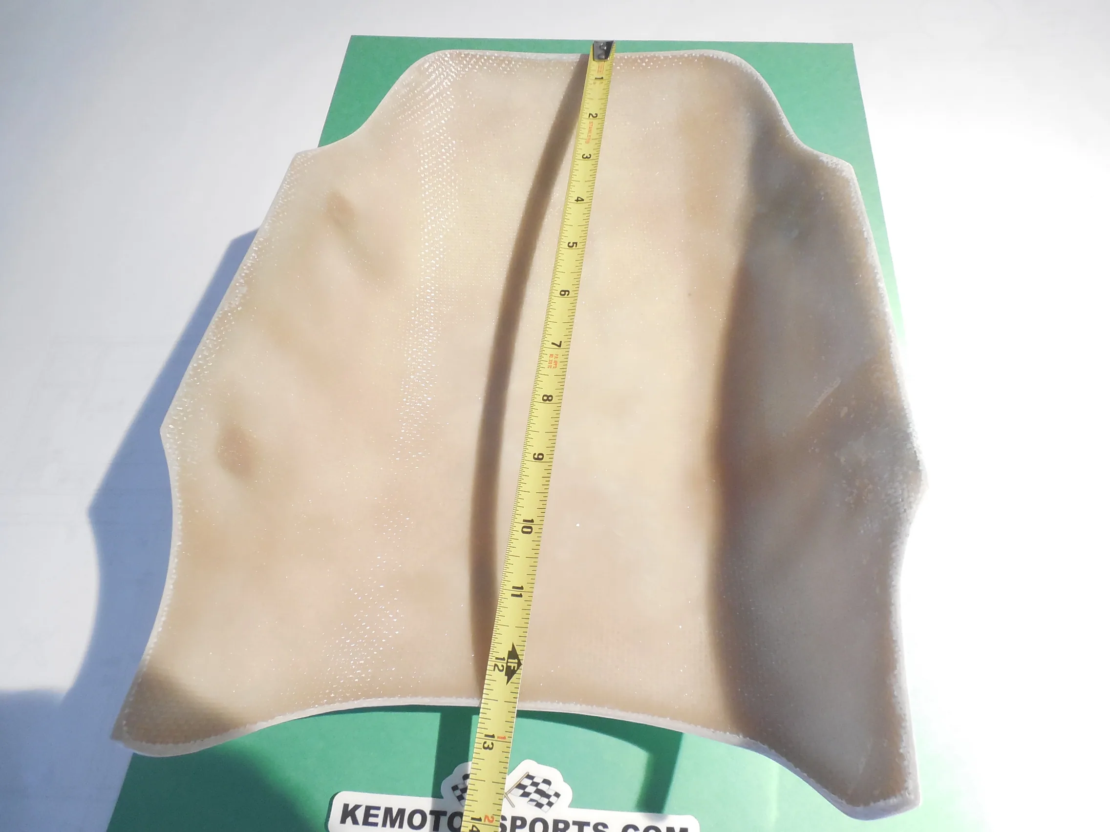 Cream-colored mesh fabric garment measured with yellow tape on green board