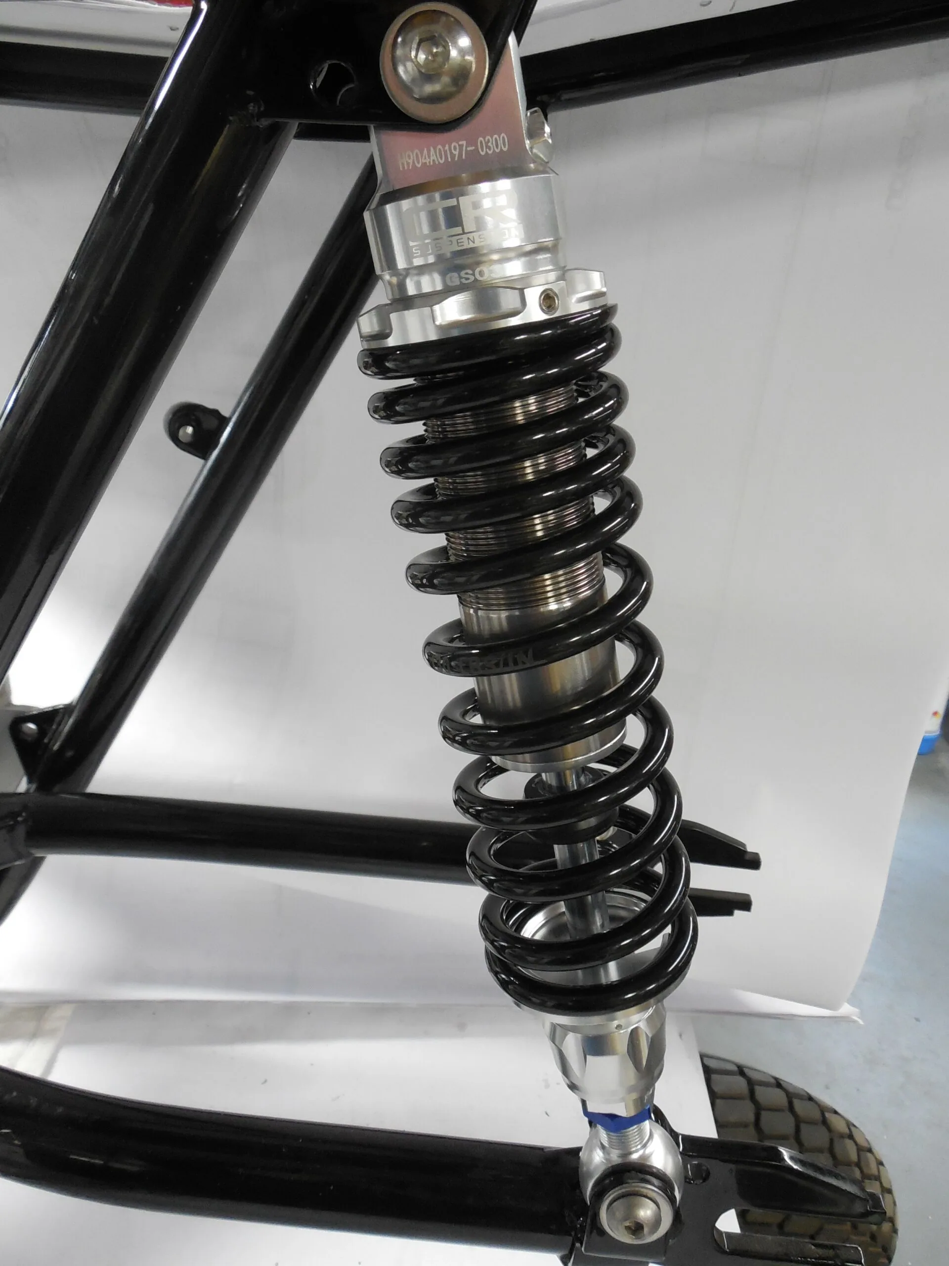 Black coil spring shock absorber suspension component mounted on motorcycle frame