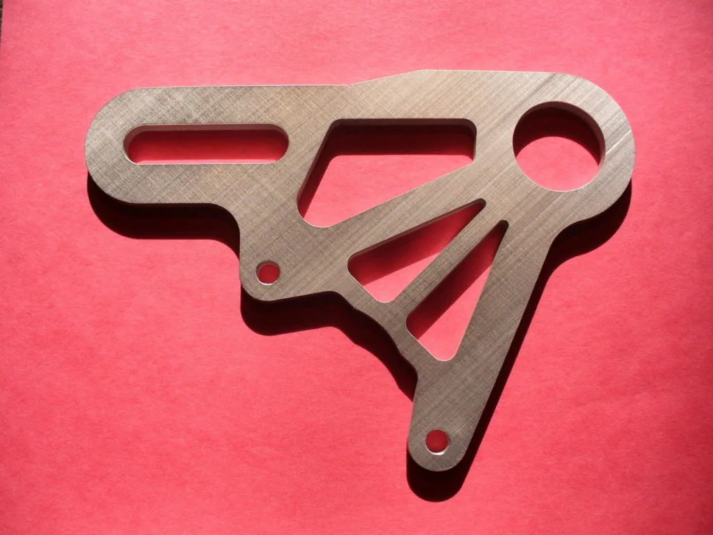 Metallic flat-track brake caliper mount with multiple cutouts and mounting holes on pink background