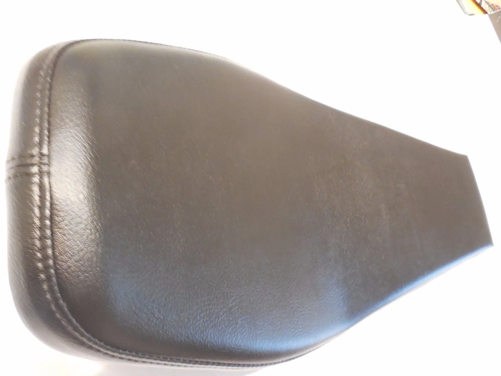 Black leather motorcycle seat with stitched seams on white background