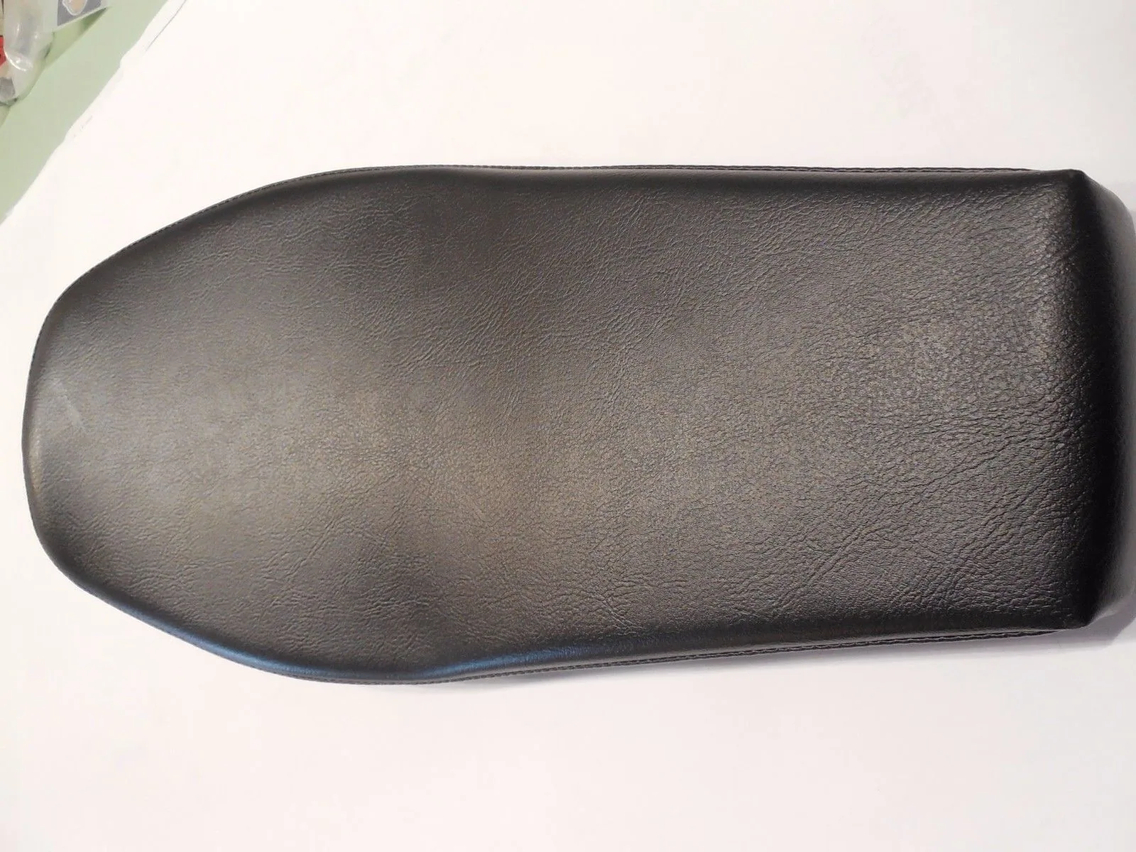 Black leather armrest pad with curved top, overhead view on white surface.