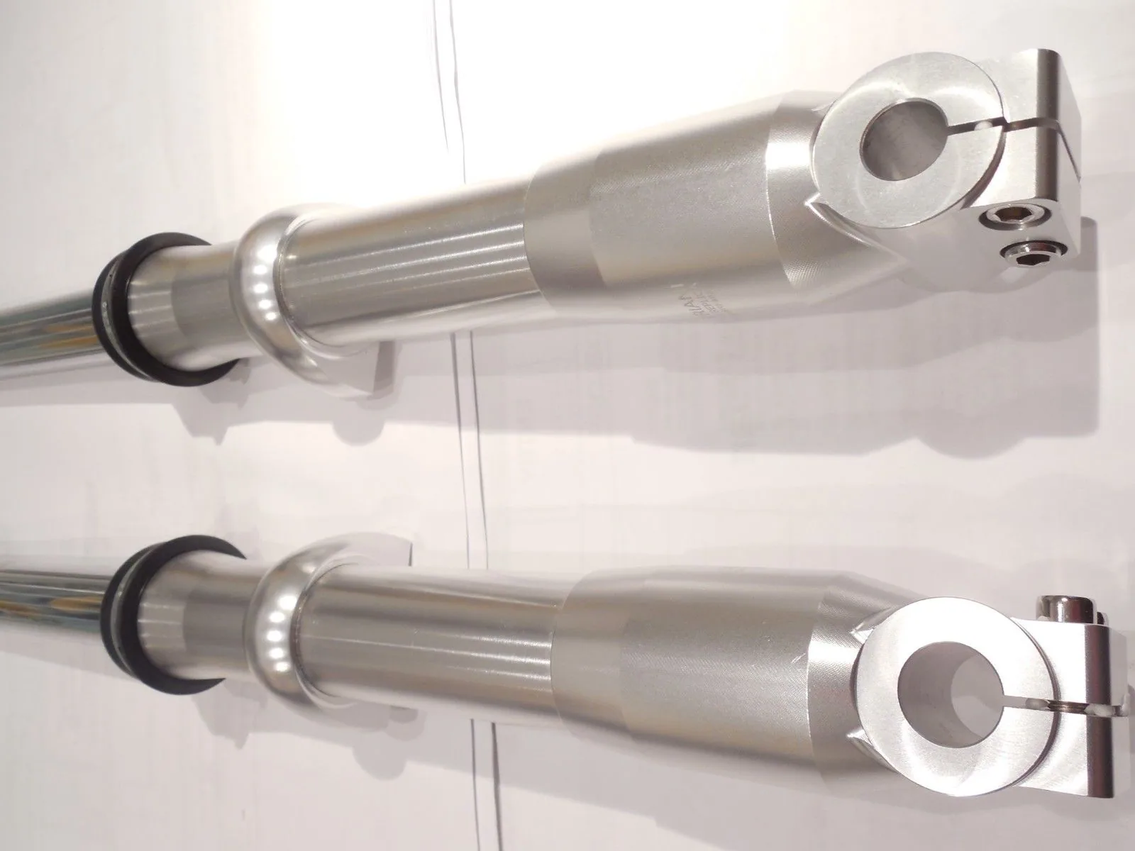 Two stainless steel window curtain rods with brackets and finials against white wall