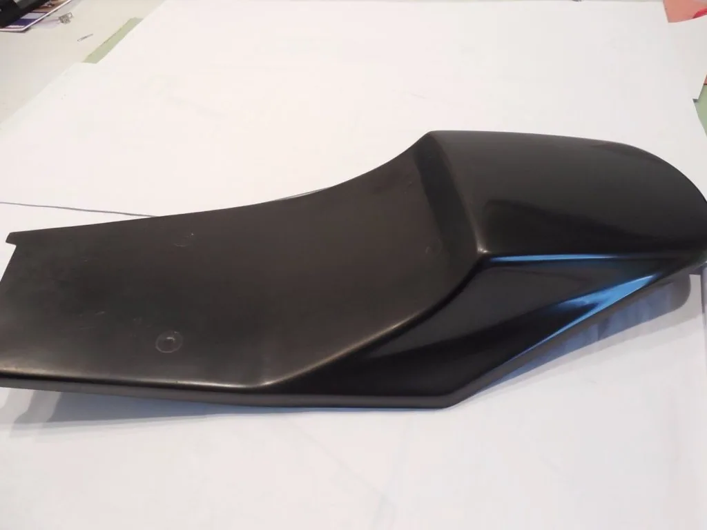 Black motorcycle seat with blue accent stripe on white surface