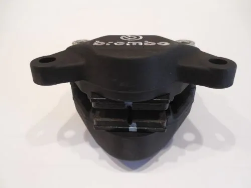 Black Brembo brake caliper with side-mounted cooling fins and mounting points on white background