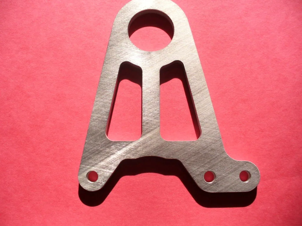 Metal bracket with three circular cutouts and curved bottom edge with mounting holes on pink background