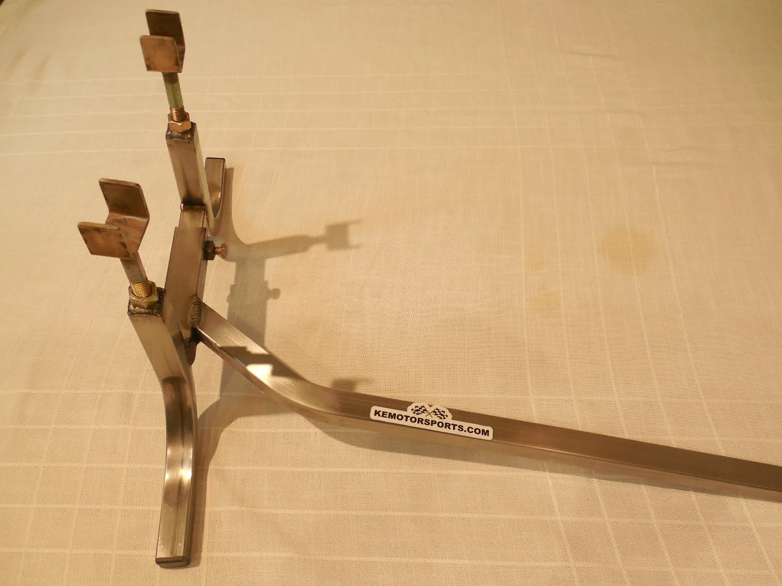 Metal motorcycle stand with adjustable arms on light surface