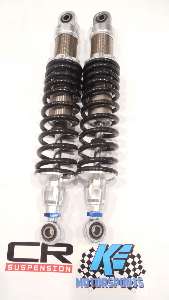 Pair of motorcycle shock absorbers with black coil springs, chrome upper tubes, and clear reservoir tubes with blue accent bands