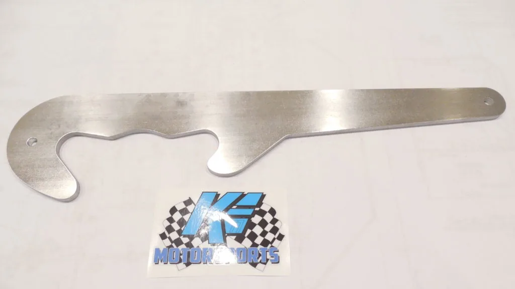 Metal tool with curved handle and heart-shaped opening, photographed against white background