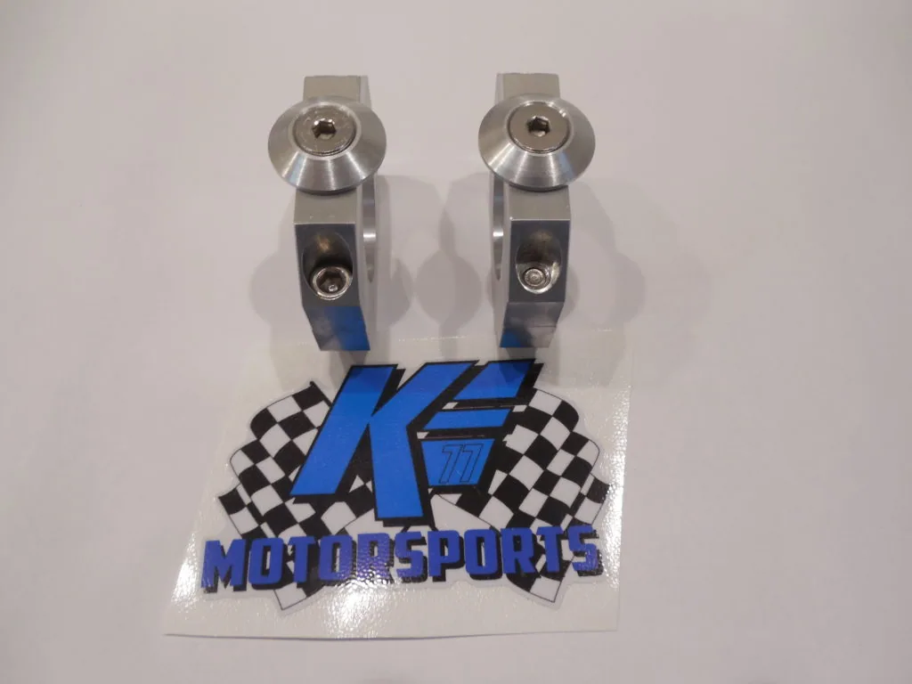 Pair of metallic rocker arm clamps with blue and black K.E. Motorsports branded sticker below