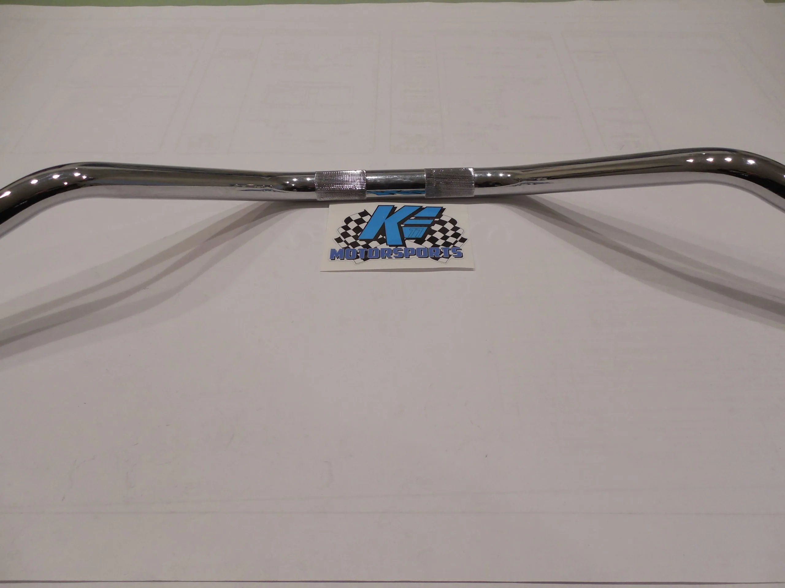 Polished chrome motorcycle handlebar with perforated grips on white background with K2 motorsports logo.