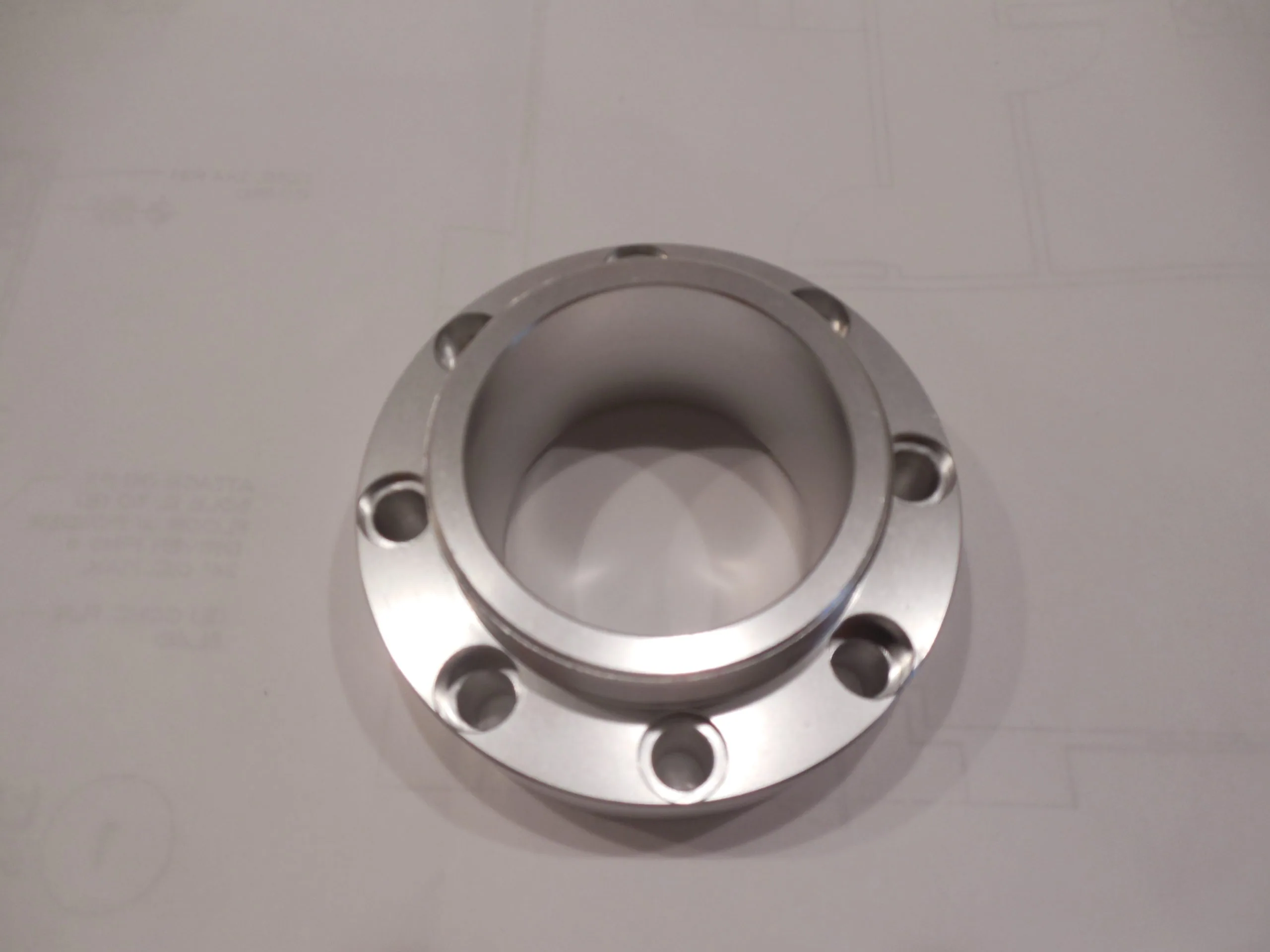 Polished stainless steel flanged coupling with bolt holes on light background