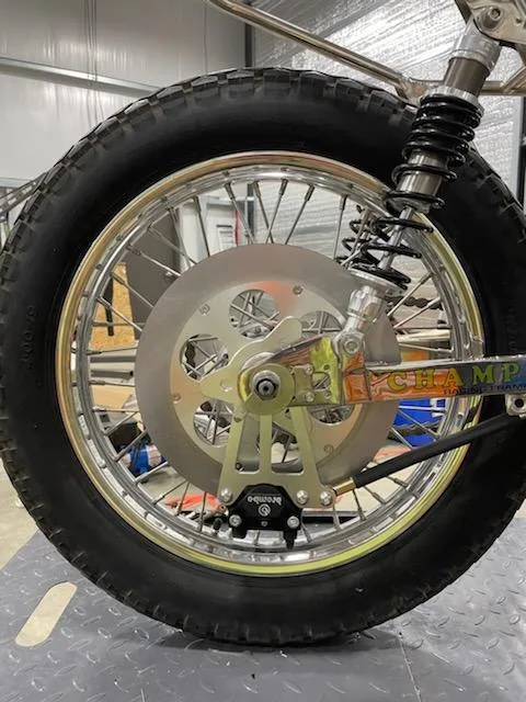 Motorcycle wheel with chrome rim, black tire, and disc brake in warehouse setting