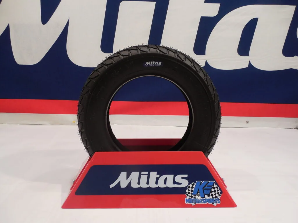 Black Mitas tire displayed on red stand at K. E. Motorsports